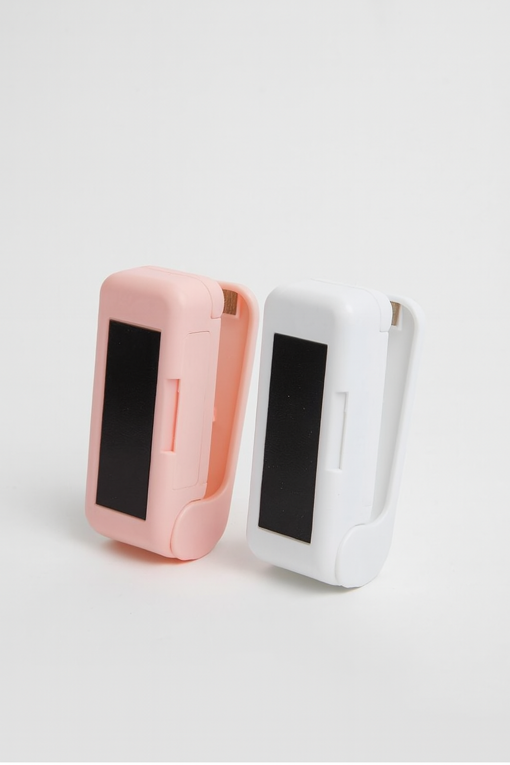 Two small electronic devices, one pink and one white, on a light gray background.