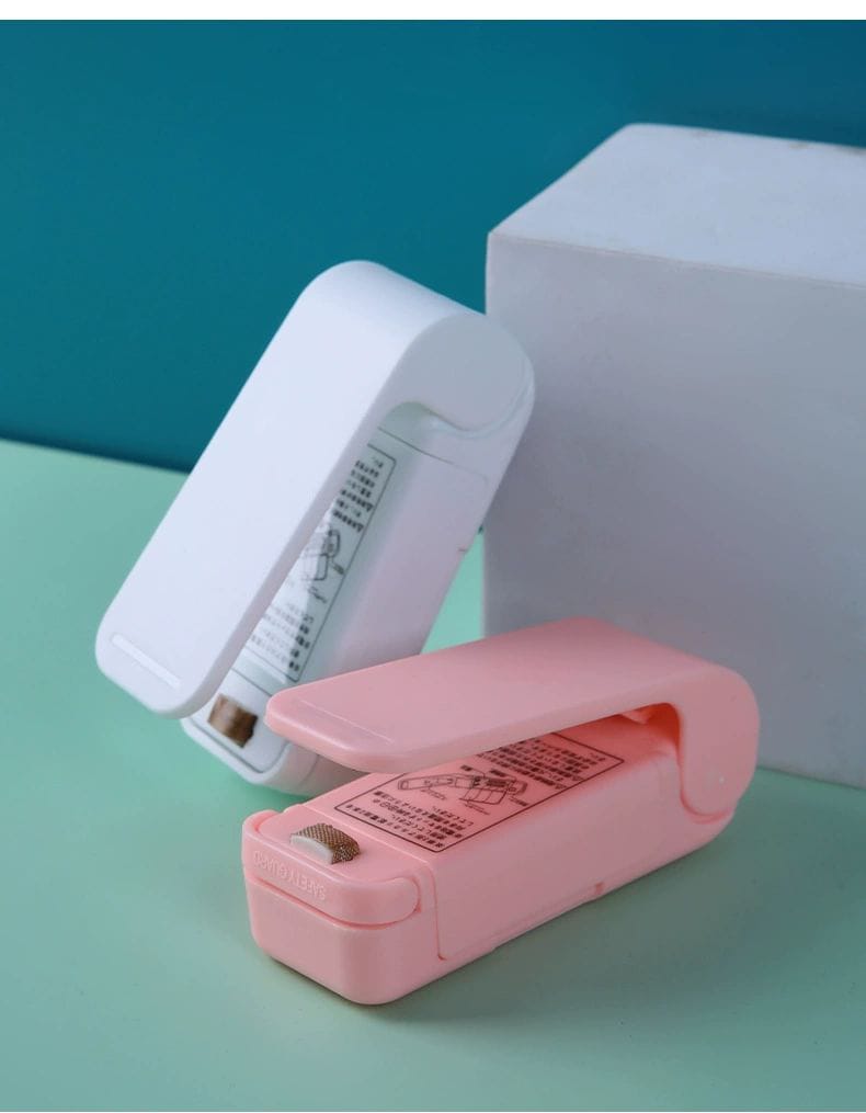 Pink and white staplers on a teal surface with a blue background