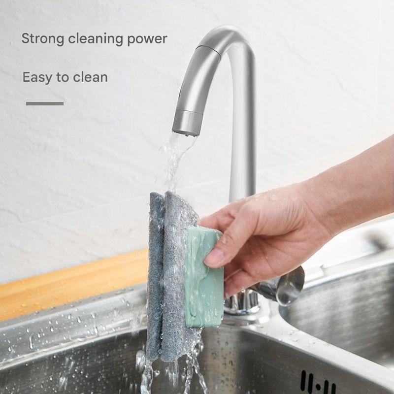 Person cleaning a kitchen sink with a sponge and water from a faucet, emphasizing strong cleaning power and ease of cleaning.