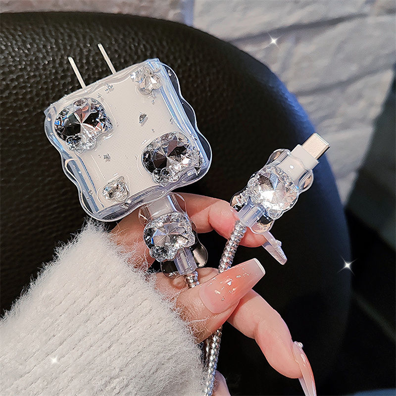 Clear phone case with decorative elements held by a person wearing a white sweater.