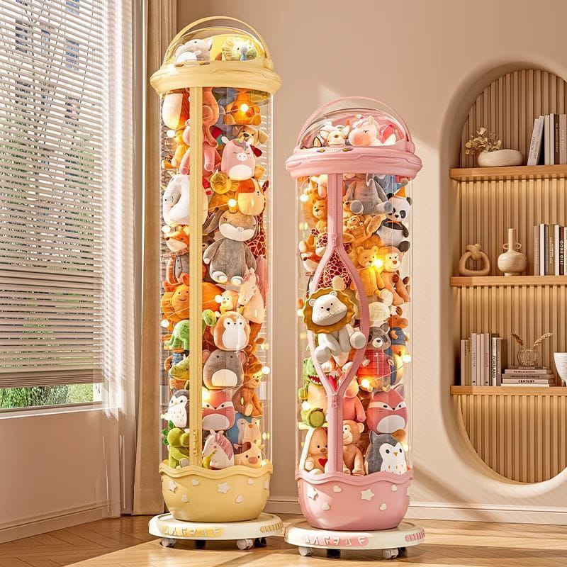 Two tall cylindrical display cases filled with colorful plush toys in a room with a window and bookshelf.