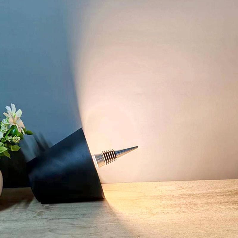 Modern black wall lamp emitting light on a wooden surface with a neutral background