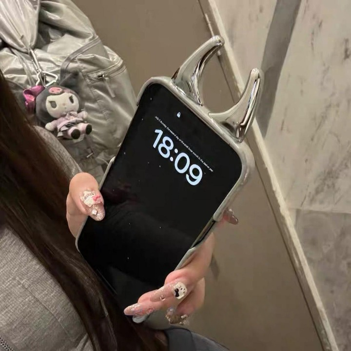 Person holding a phone with a digital clock display, wearing a silver jacket.