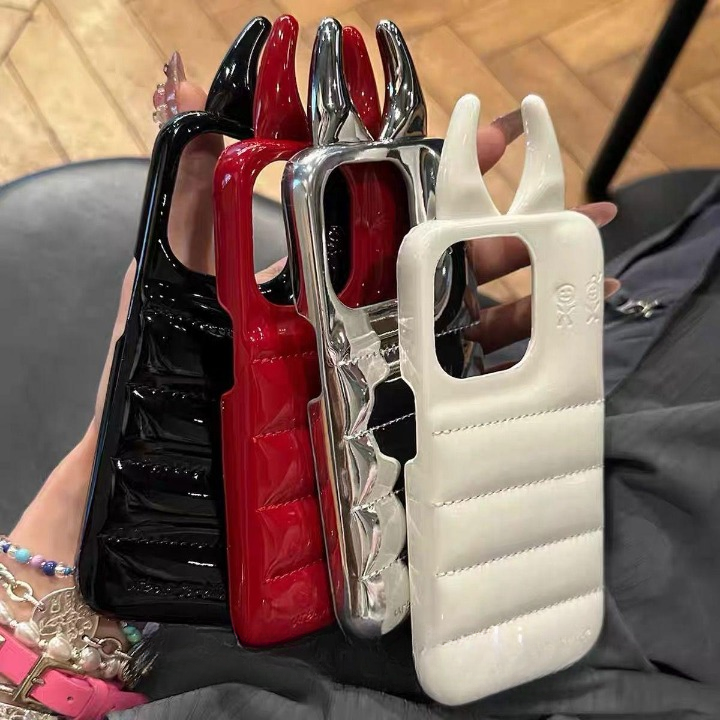 Four phone cases in black, red, silver, and white held by a person.