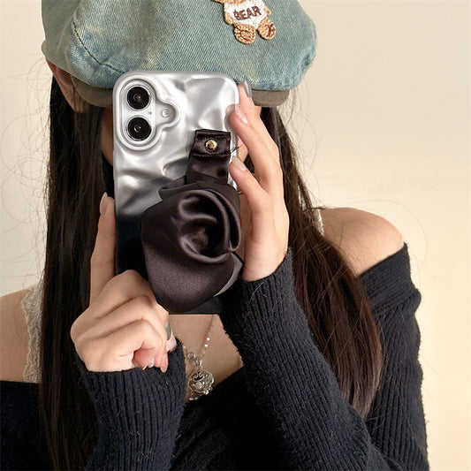 Person holding a phone with a rose gold case and brown flower accessory.