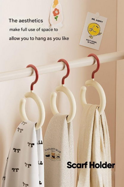 Scarf holder with scarves and a decorative card on a beige wall.