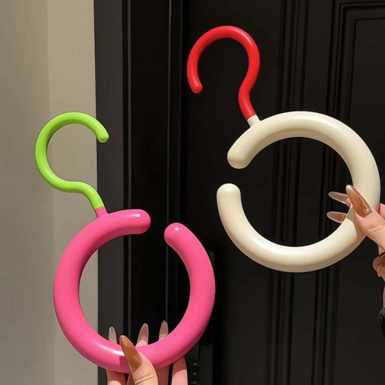 Colorful balloon arch hooks against a black door.