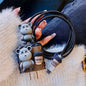 Coiled black USB cable with bear and coffee cup charms on a textured surface