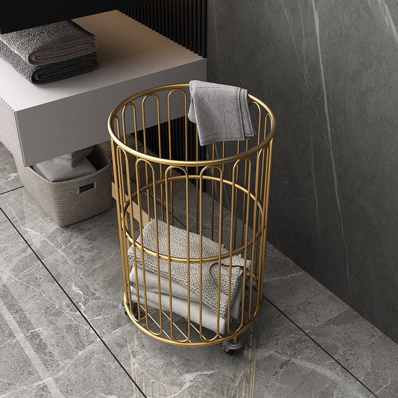 Gold wire basket with towels on a tiled floor in a bathroom setting
