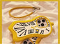 Phone case with clock design and yellow strap on a soft fabric background