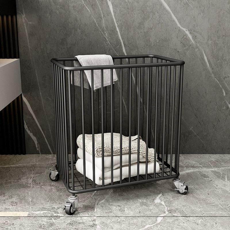 Black metal basket with towels on a stone floor against a marble wall